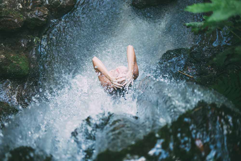 Woman taking a cold shower under a waterfall evoking a meditative state